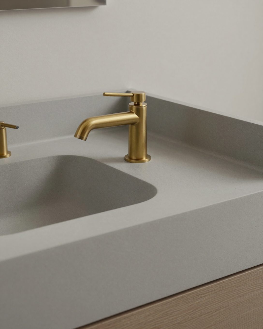 Illustration: a microcement vanity top with an integrated basin and a curved edge, soft grey, brass tap
